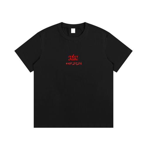 White Suku Essential Cotton T-Shirt with bold red logo on chest, oversized fit, soft premium cotton, styled in a studio setting.