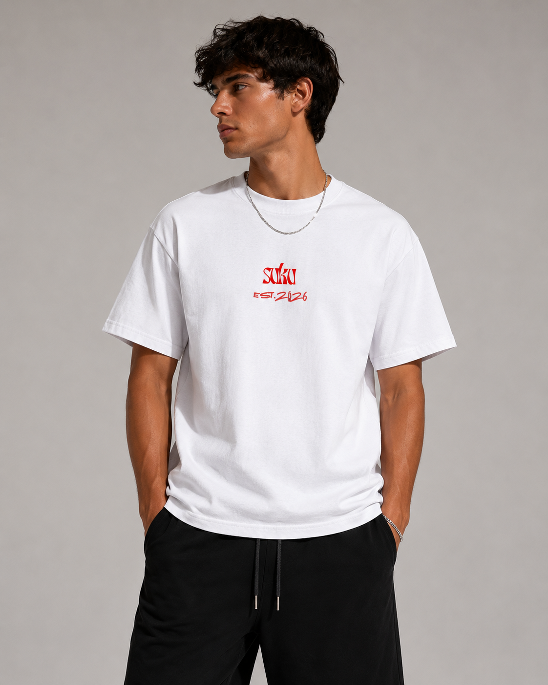 White oversized cotton T-shirt by Suku with bold red logo on chest, soft premium fabric, relaxed fit, styled on a model in a studio.