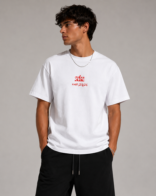 White oversized cotton T-shirt by Suku with bold red logo on chest, soft premium fabric, relaxed fit, styled on a model in a studio.